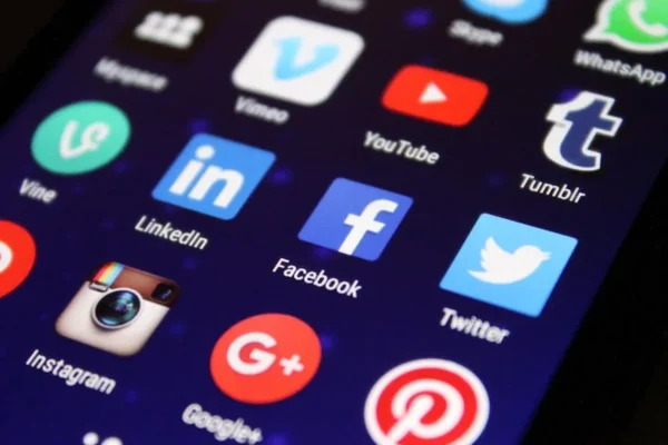 Close-up of a smartphone screen showing various social media app icons such as Facebook and Twitter.
