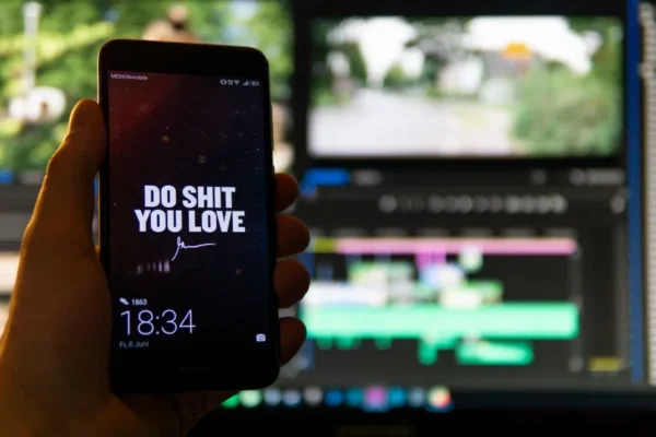 Close-up of a smartphone displaying an inspirational message against a video editing background.