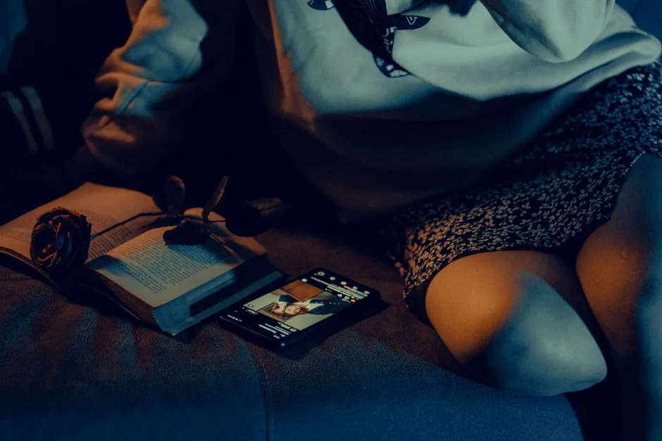 Cozy scene with a book, smartphone, and low lighting conveying a relaxed evening at home.