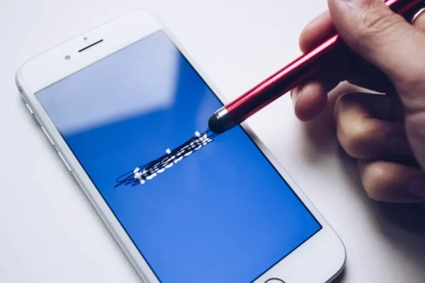 Close-up of a smartphone with a stylus crossing out text on its screen.