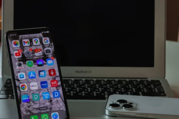 Close-up of a smartphone and laptop on a desk, displaying productivity and connectivity.