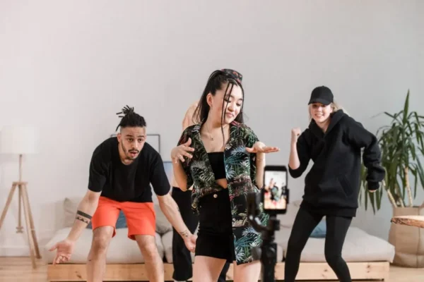 Group of diverse young adults dancing and recording content indoors with a smartphone.